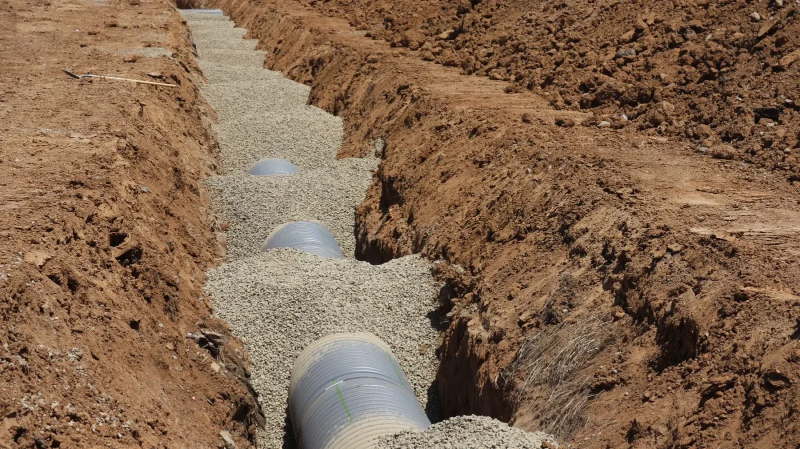 Stock photograph of drainage pipe bedded in a gravel trench