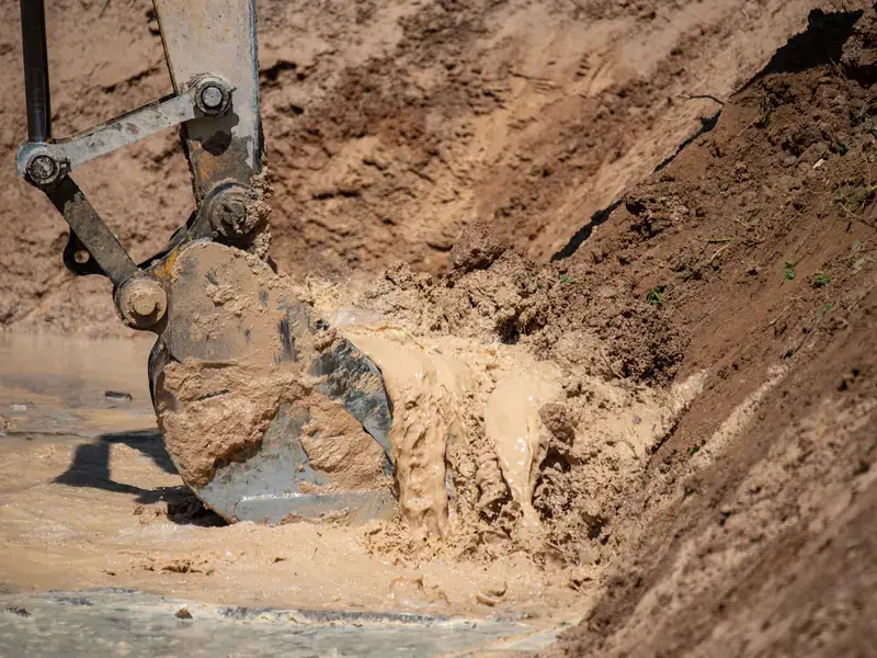 Excavator bucket working in wet soil in Magnolia, Illinois